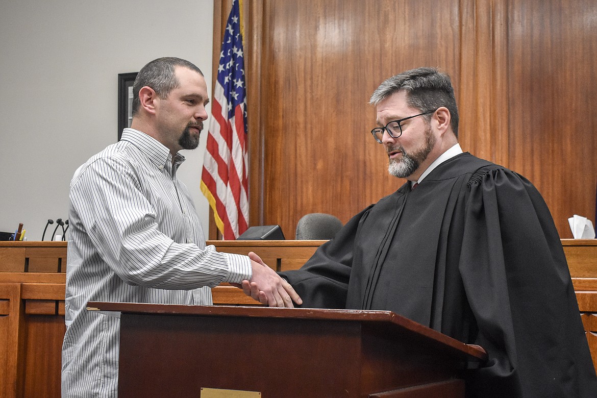 Montana 19th Judicial District Judge Matt Cuffe shakes hands withnew Lincoln County Commissioner Josh Letcher, representing District 3, in the County Courthouse Wednesday. (Ben Kibbey/The Western News)