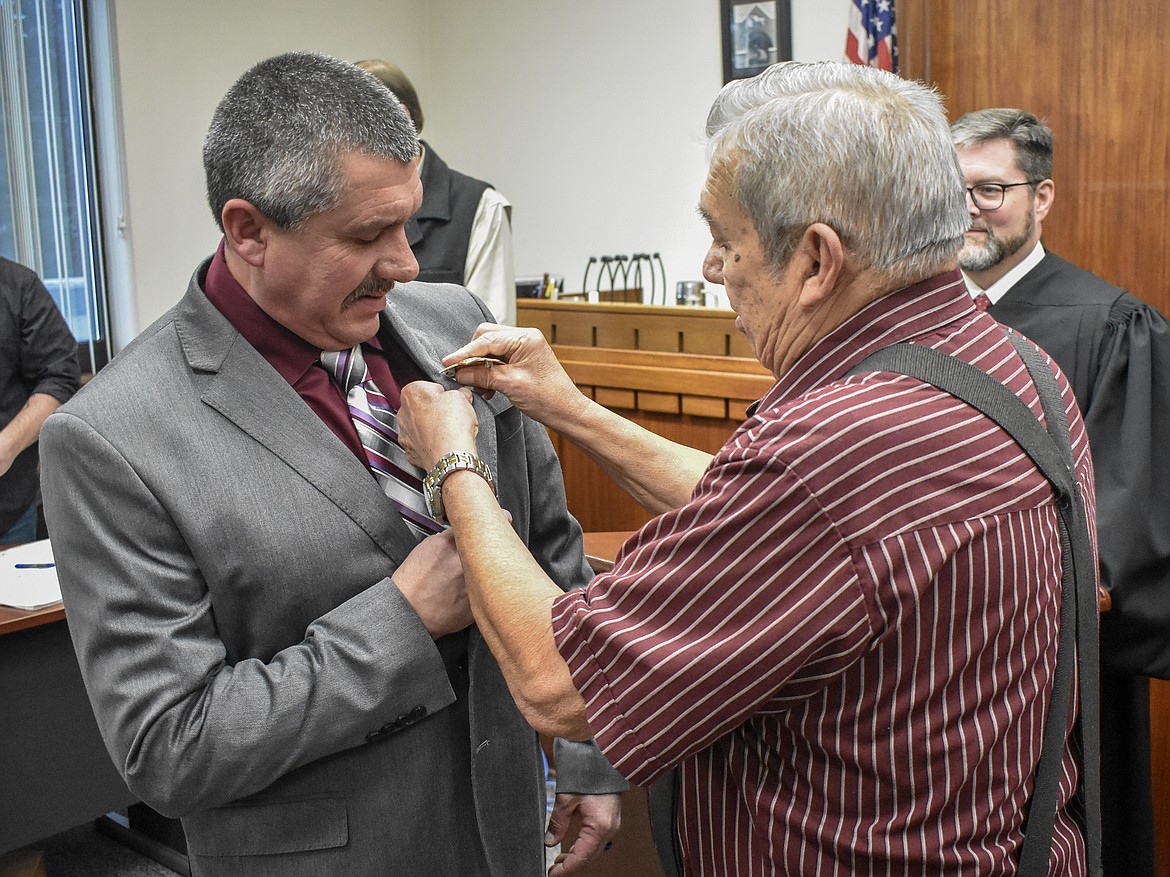 James Short pins his son, new Lincoln County Sheriff Darren Short, with his badge after his swearing in at the County Courthouse Wednesday. Though the pinning would normally be done by outgoing Sheriff Roby Bowe, Bowe offered the honor to Short&#146;s father. (Ben Kibbey/The Western News)