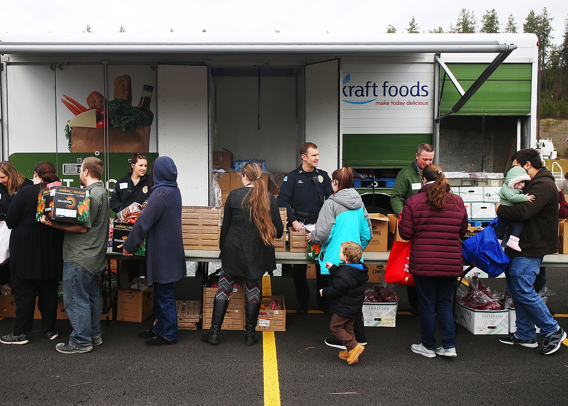 Volunteers with the Post Falls Police, Second Harvest, Idaho Central Credit Union and Kootenai County Fire and Rescue help distribute groceries for those in need at a free food distribution event Wednesday in Post Falls. The event served 254 families. (LOREN BENOIT/Press)