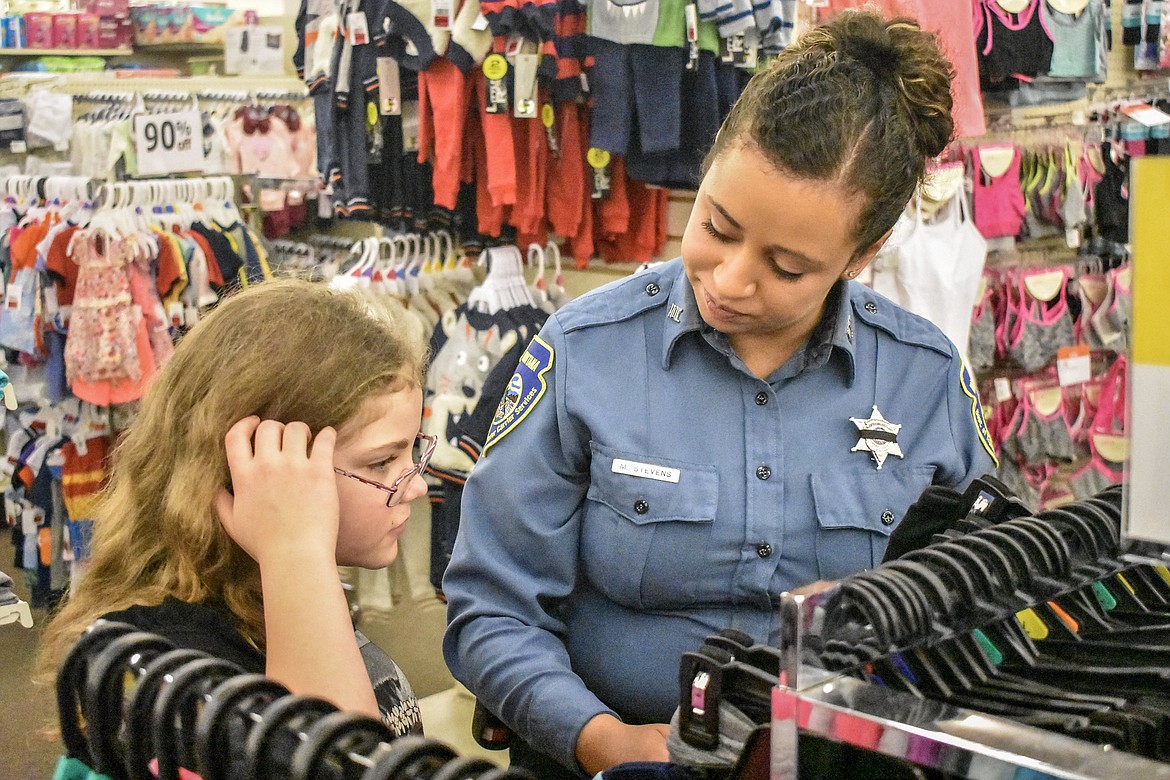 MDOT Motor Carrier Services Officer Meghan Stevens helps Zoe Forman find presents for her family during Shop With a Cop in Libby Monday. (Ben Kibbey/The Western News)