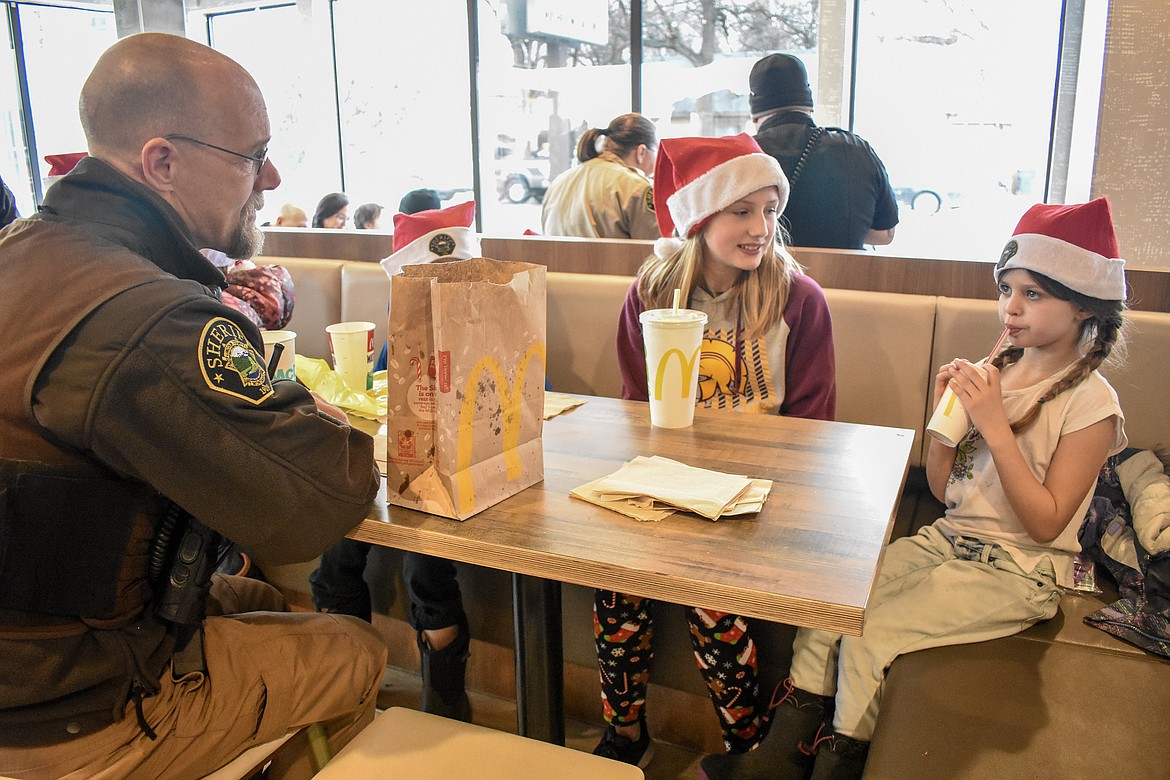 Lincoln County Sheriff&#146;s deputy Brent Faulkner talks with Autumn Fisher and Jazlyn Kelso over lunch during Shop With a Cop in Libby Monday. Fisher was helping her dad, Deputy Ben Fisher, to shop with Kelso for presents for her family. (Ben Kibbey/The Western News)