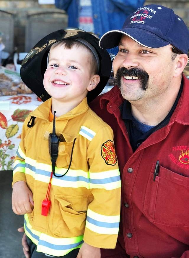 Jace Russell, pictured with his dad, Plains-Paradise Rural Fire Department chief, smiles after eating a homemade cookie during a fundraiser for the Junior Firefighter Scholarship Fund. (CFVP file photo)