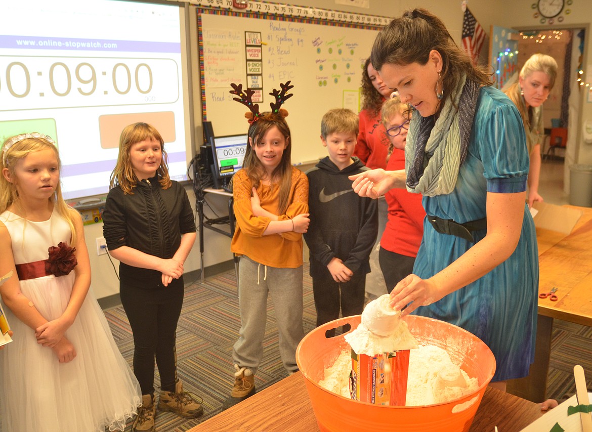 A science and construction activity was part of Winter Wonderland events on Dec. 20 at Plains Schools. Above, students watch Ms. McGee dump flour (simulating snow) on the roof of a house a student built to determine how much of a load of snow  the roof could hold.