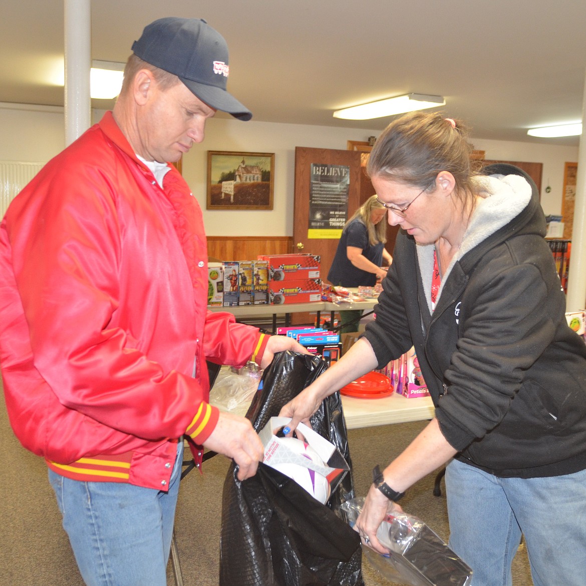 With help from Mike Dennison of the Marine Corps League Detachment 1041, Diana Elrod of Plains loads toys in a bag during pickup for the Toys for Tots program on Dec. 15 at Gospel Mountain Assembly of God Church in Thompson Falls.