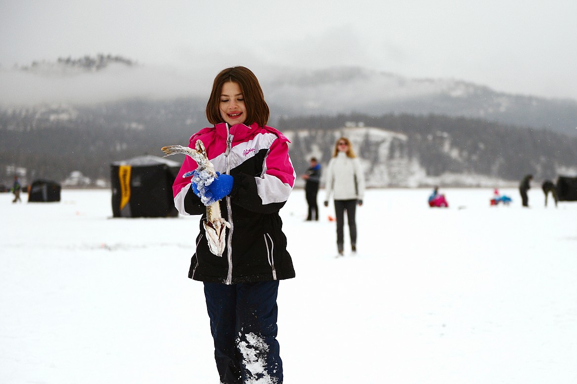 Shaylee Kitzmiller, 11, of Kalispell, smiles as she carries in a pike to be measured at the Sunriser Lions ice fishing derby at Smith Lake on Saturday. (Casey Kreider/Daily Inter Lake)