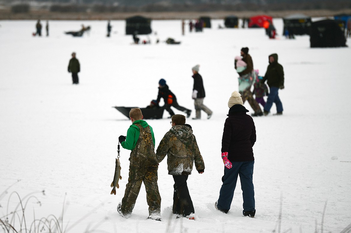 People walk their catches to shore to be measured at the Sunriser Lions ice fishing derby at Smith Lake on Saturday. (Casey Kreider/Daily Inter Lake)