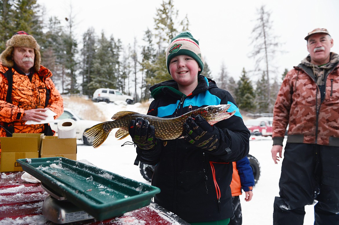 Dane Reynolds, of Kalispell, holds a northern pike that weighed in at 2.69 lbs. at the Sunriser Lions ice fishing derby at Smith Lake on Saturday. To his left and right are Warren Illi and Joe Rudolph of the Flathead Chapter of Walleyes Unlimited. (Casey Kreider/Daily Inter Lake)