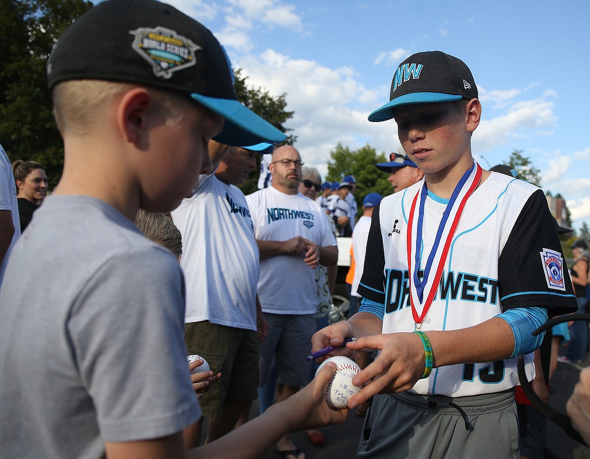 Christopher Reynolds signs Connor Johnson's baseball during the Coeur d'Alene Little League parade, Aug. 30, 2018 in downtown Coeur d'Alene. The all-stars team made a run all the way to Williamsport, PA this year for the Little League World Series and is the second in Idaho's history to make it to the series. (LOREN BENOIT/Press File)
