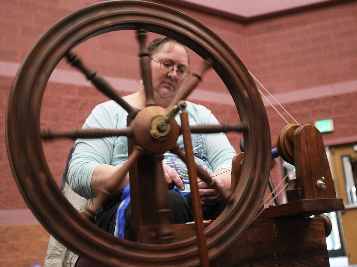 Iverna McAnulty spins a soft blue wool on the walnut wood spinning wheel her dad made 35 years ago as she participates in the spin in on Saturday.
