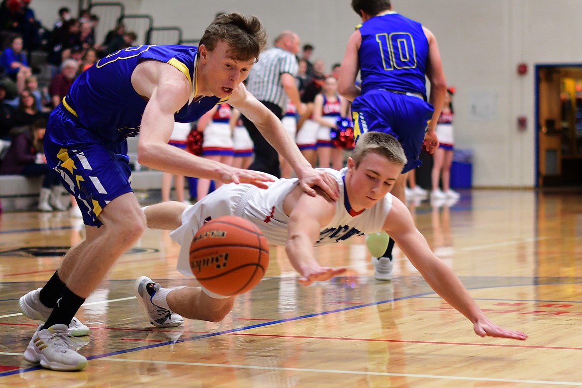 Libby&#146;s Ryggs Johnston battles Columbia Falls guard Logan Bechtel for a loose ball in the first quarter Thursday. (Jeremy Weber photo)