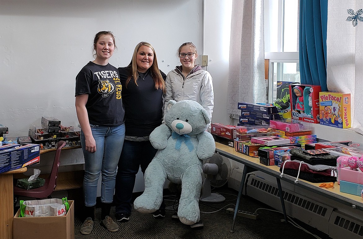 Grace King (left), Kaylee Crabb (middle) and Emma Davis (right) display gifts purchased with funds raised by St. Regis students to help families in need during the holiday season. (Photo courtesy of Joe Steele)
