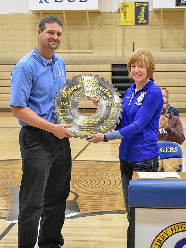 Libby High School Athletic Director Nik Rewerts presents a saw blade painted with her many accomplishments to Libby Volleyball Head Coach Cindy Ostrem-Johnston during the Fall Awards Assembly Nov. 15. (Ben Kibbey/The Western News)