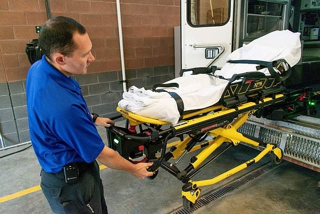Vincent Brown, an Advanced EMT with Libby Volunteer Ambulance, demonstrates the function of one of LVA&#146;s ambulances equipped with an arm to assist lifting the stretcher in and out. With ambulance services increasingly dependent on volunteers staying on well past retirement age, the assist device, which cost more than $20,000, helps a lot, Brown said. (Ben Kibbey/The Western News)