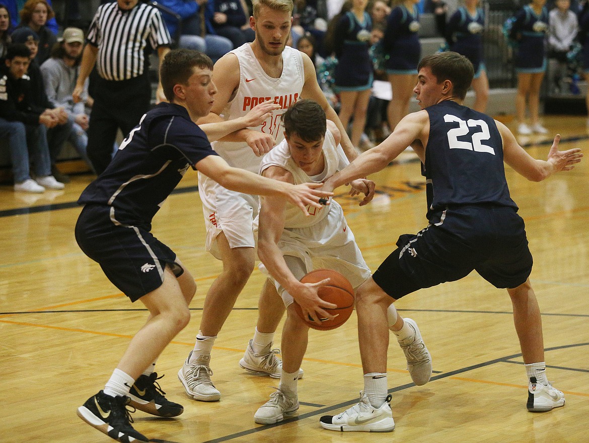 Post Falls guard Cole Rutherford dribbles the ball between Lake City defenders Ben Janke, left, and Brayden Sundstrom during Tuesday night's game in Post Falls. (LOREN BENOIT/Press)