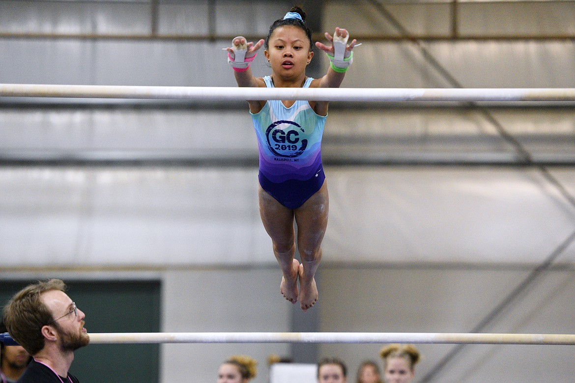 Kaitleen To, from Flathead Gymnastics Academy, competes on the uneven bars at the 4th annual Glacier Challenge at the Flathead County Fairgrounds Trade Center in Kalispell on Saturday. At bottom left is coach David Tighe. (Casey Kreider/Daily Inter Lake)