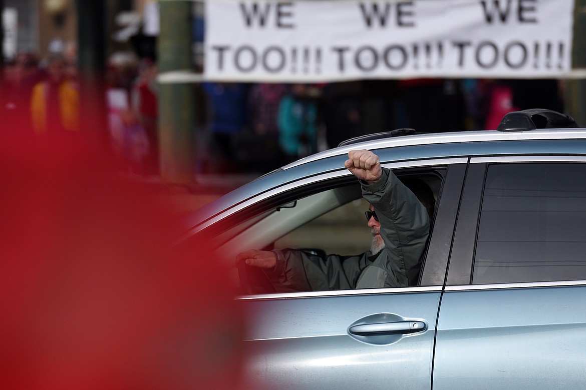 A man honks and holds his fist out of the window towards a group rallying in support of President Donald Trump along East Center Street, across the street from the Kalispell Women's March held at Depot Park in Kalispell on Saturday. (Casey Kreider/Daily Inter Lake)