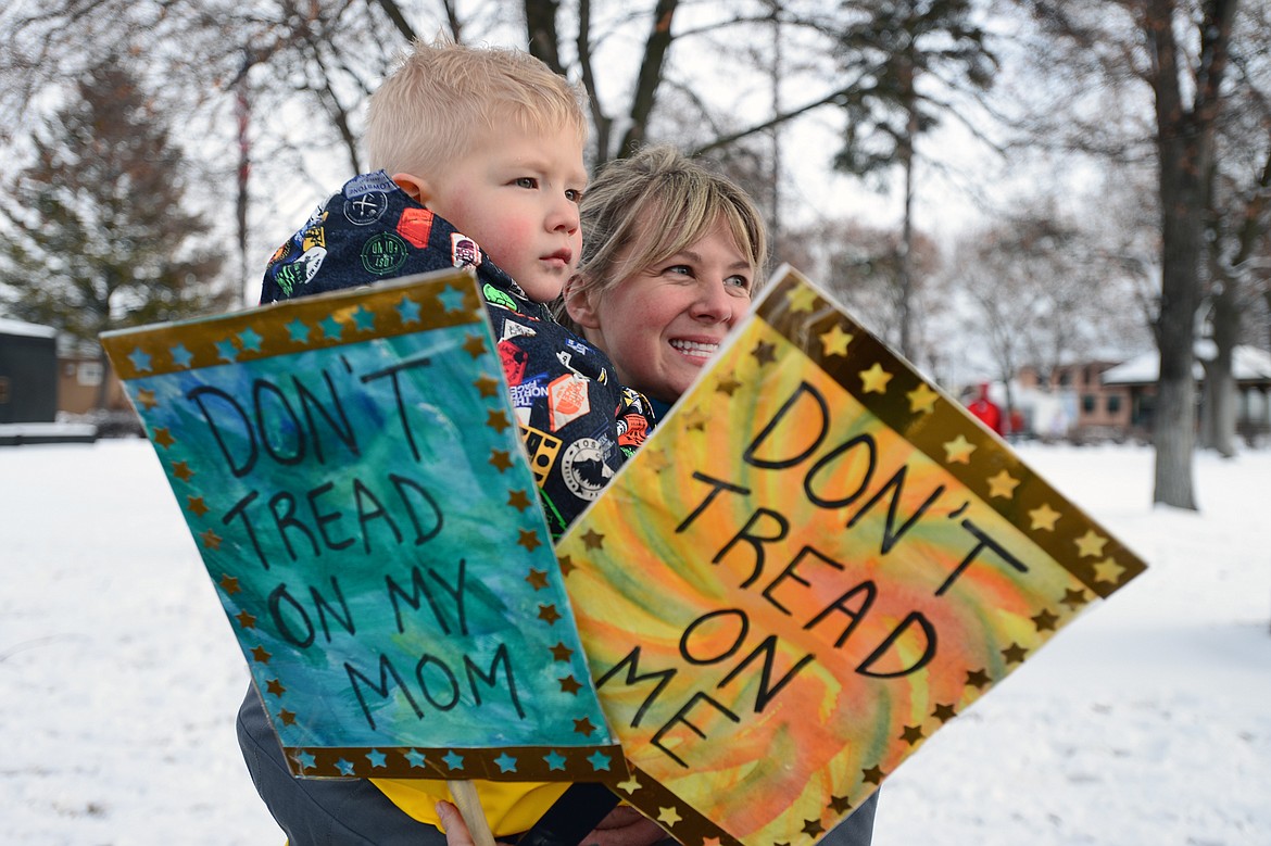 Jesse Feist and her son Finn, of Kalispell, hold signs outside the Kalispell Women's March at Depot Park on Saturday. (Casey Kreider/Daily Inter Lake)