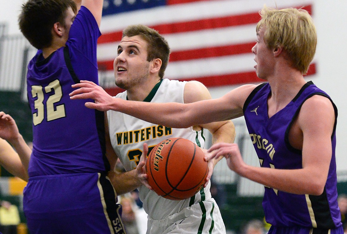 Whitefish's Ryan Kemm (33) drives to the basket between Polson's Colton Graham (32) and Trevor Schultz (14) at Whitefish High School on Friday. (Casey Kreider/Daily Inter Lake)