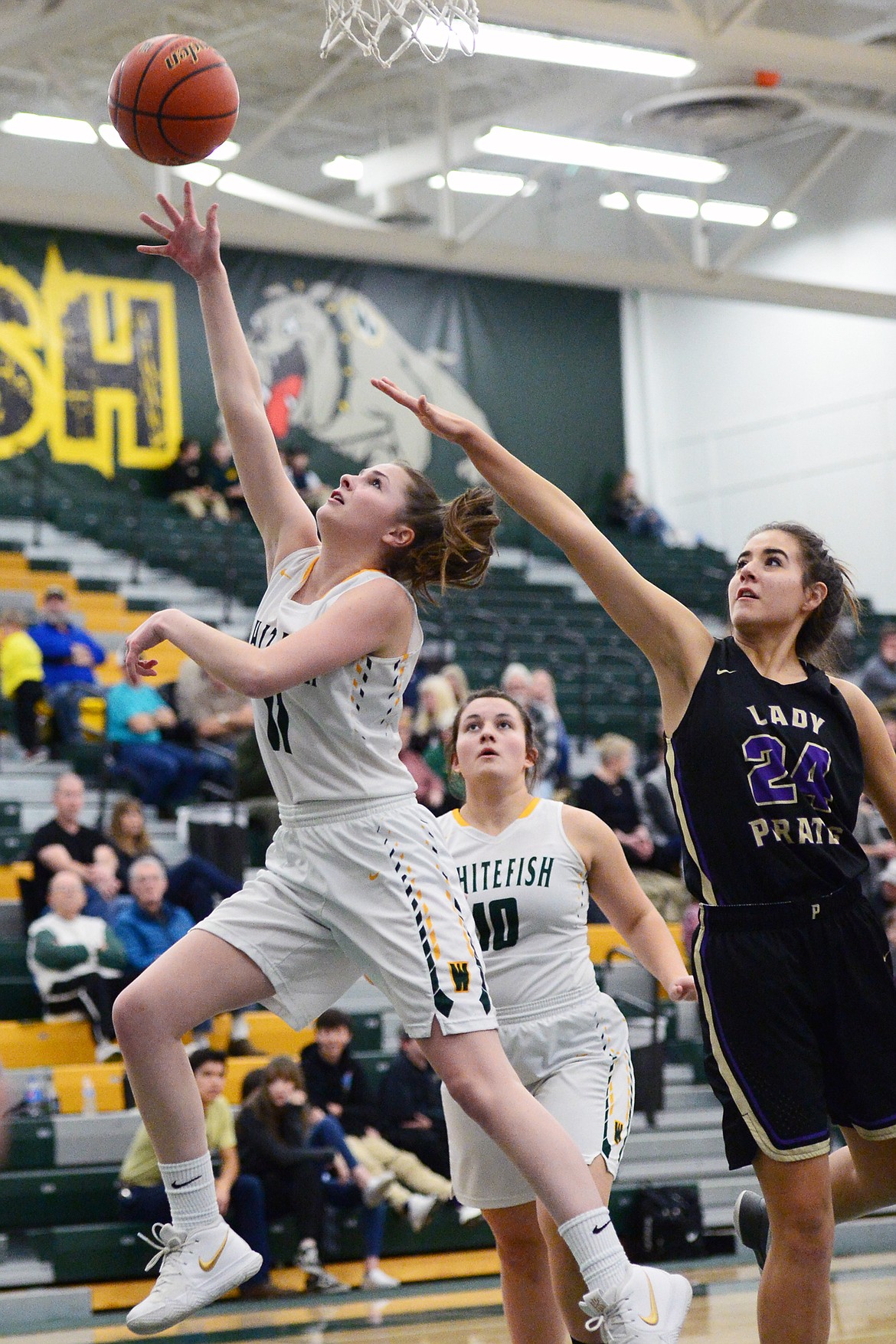 Whitefish's Claire Carloss (11) drives to the basket in front of Polson's Misty Tenas (24) at Whitefish High School on Friday. (Casey Kreider/Daily Inter Lake)