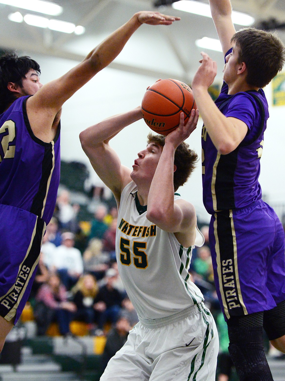 Whitefish's Dillon Botner (55) pump-fakes under the basket between Polson's Kordell Walker (42) and Colton Graham (32) at Whitefish High School on Friday. (Casey Kreider/Daily Inter Lake)