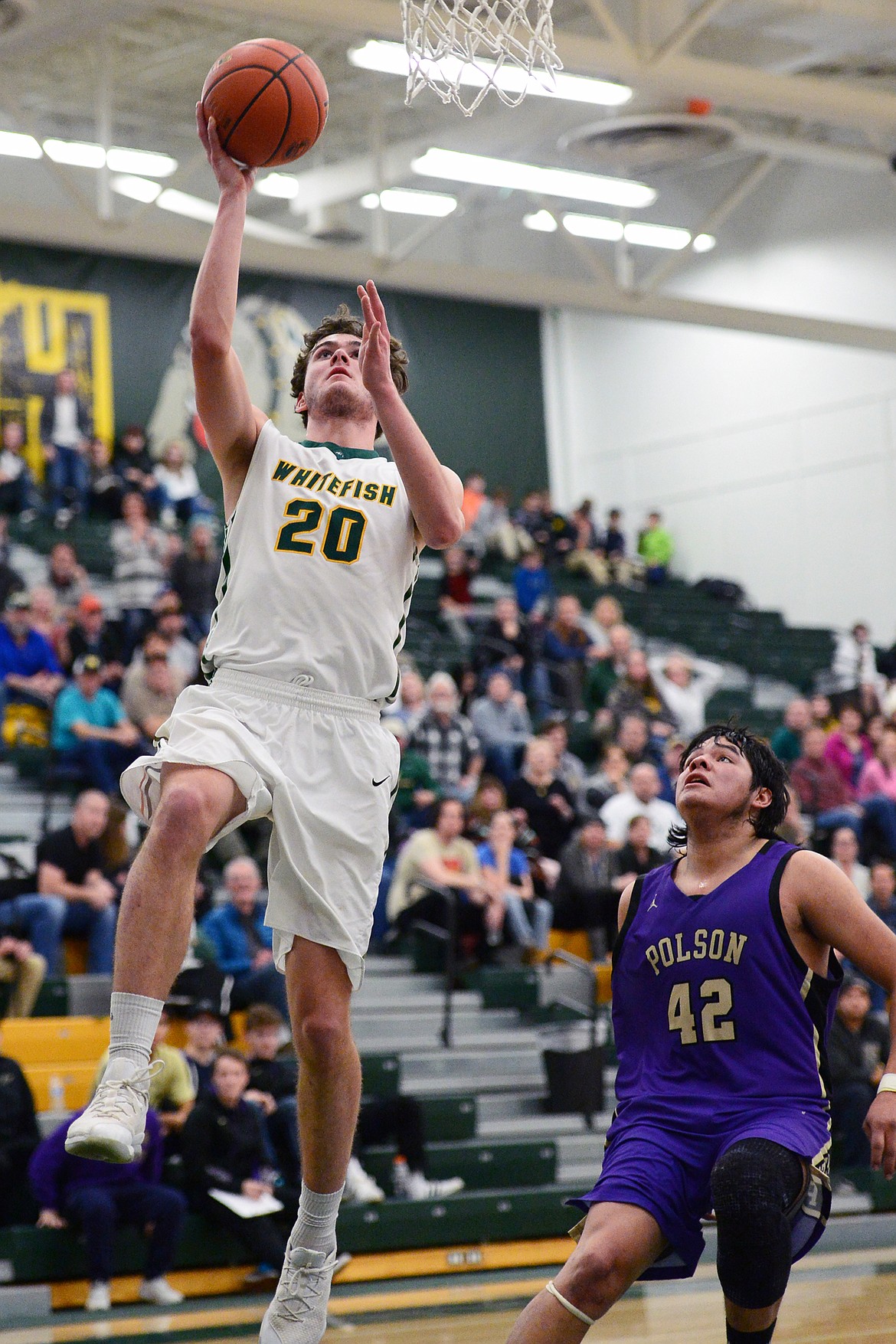 Whitefish's Sam Menicke (20) heads to the hoop for a layup in front of Polson's Kordell Walker (42) at Whitefish High School on Friday. (Casey Kreider/Daily Inter Lake)