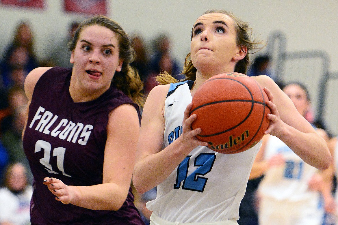 Bigfork's Heidi Schneller (12) drives to the basket with Florence's Makenna Liles (31) trailing in defense at Bigfork High School on Saturday. (Casey Kreider/Daily Inter Lake)