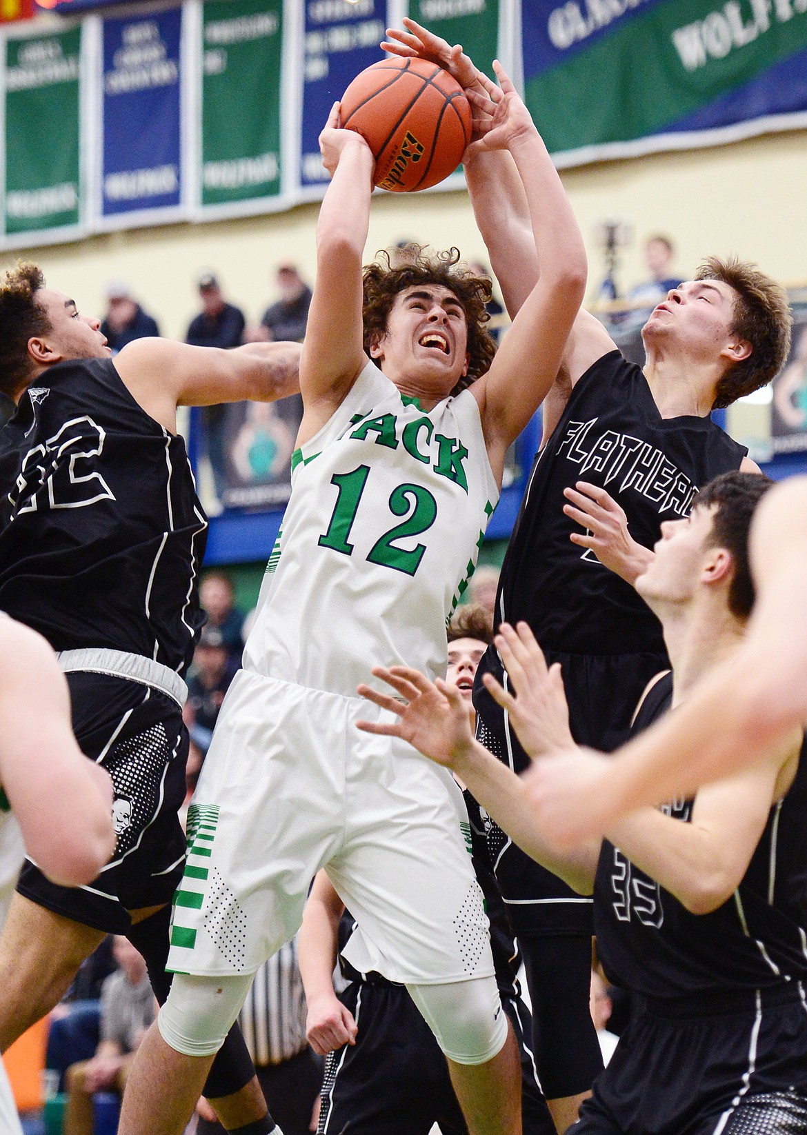 Glacier's Weston Price (12) powers to the rim between Flathead's Anthony Jones (42) and Tannen Beyl (5) during a crosstown matchup at Glacier High School on Friday. Beyl was whistled for a foul on the play. (Casey Kreider/Daily Inter Lake)