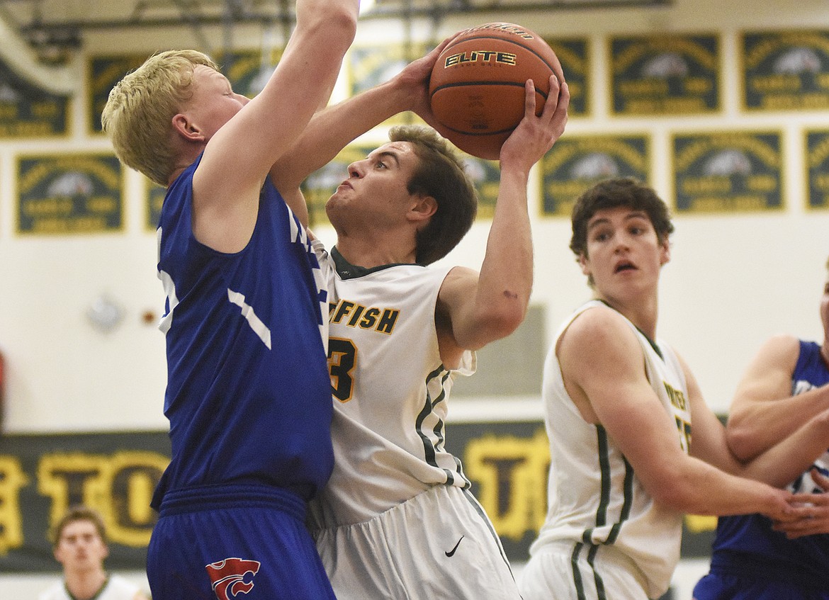 Ryan Kemm gets hammered by a Wildcat defender during the Dogs&#146; 60-45 rivalry win on Thursday. (Daniel McKay/Whitefish Pilot)