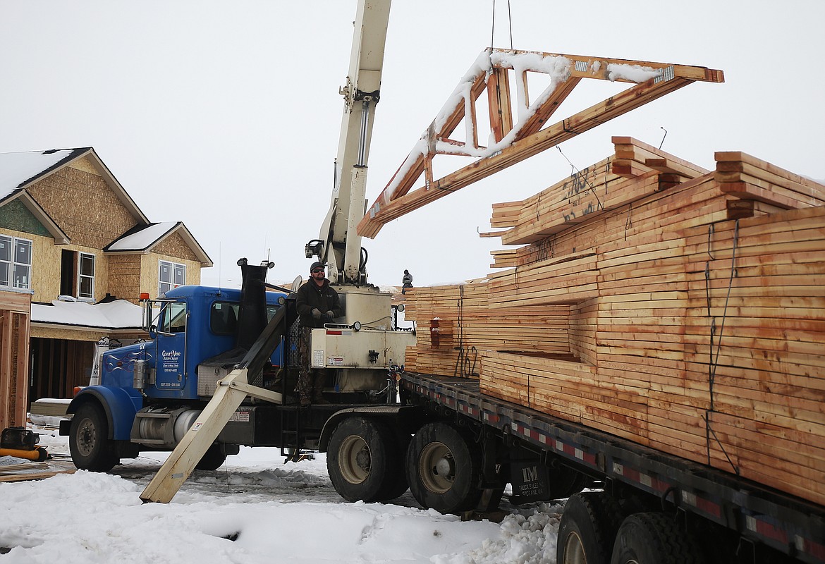 Mark Carrington with Coeur d'Alene Building Supply unloads trestles for a new home along Glenroe Avenue in Post Falls on Friday. (LOREN BENOIT/Press)