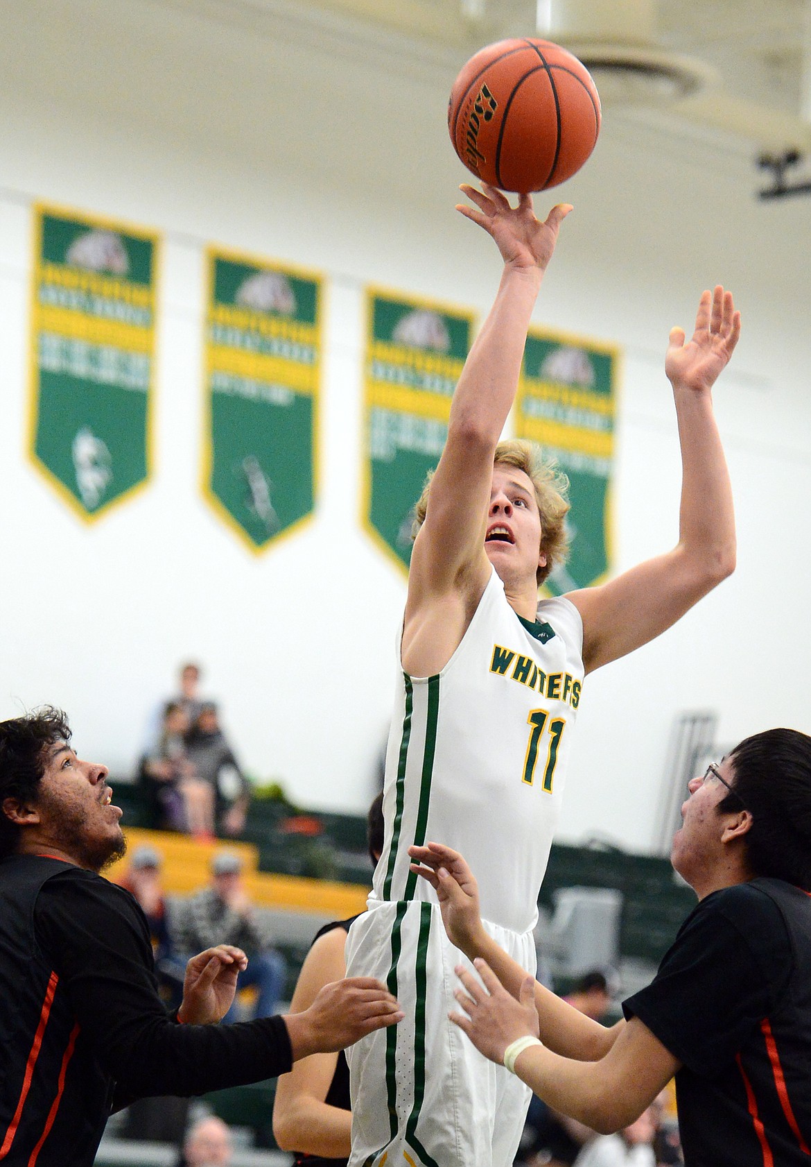 Whitefish's Mark Anderson (11) releases a shot between Ronan defenders Bubba Bush (23) and Aidan Birdinground (15) at Whitefish High School on Tuesday. (Casey Kreider/Daily Inter Lake)