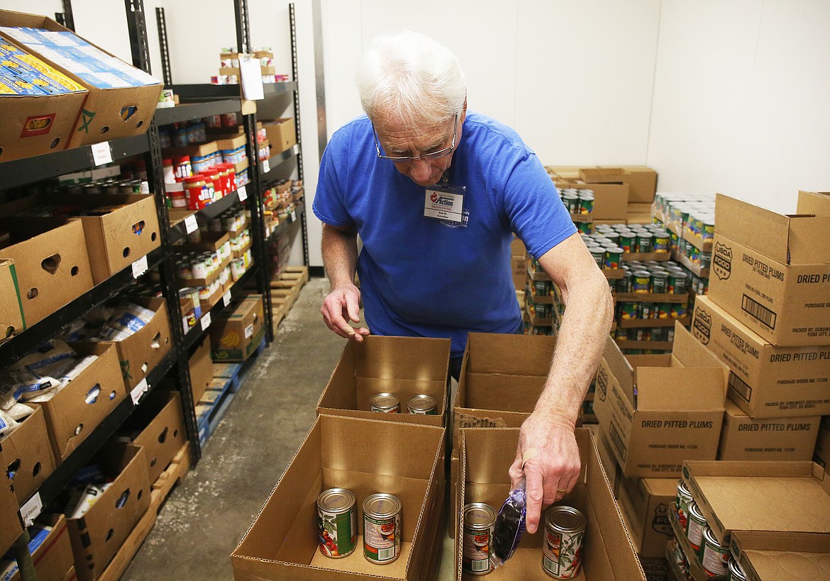 Volunteer Bob Mattfeld places donated goods into a box for families in need at Community Action Partnership on Wednesday. (LOREN BENOIT/Press)