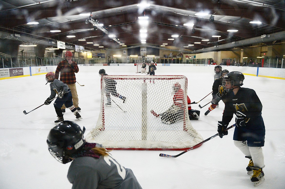 Players pursue the puck after a shot goes wide of the net during a Yeti League game.