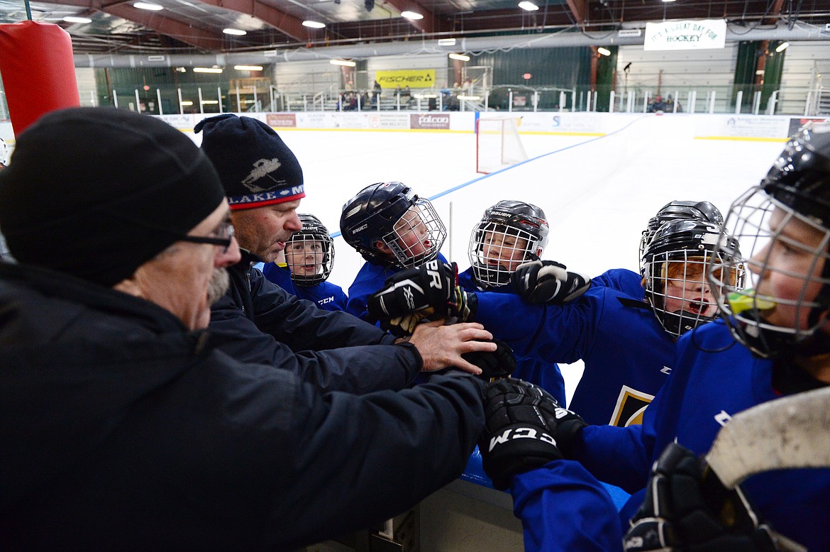 Players and coaches on the blue team huddle before the start of a game.