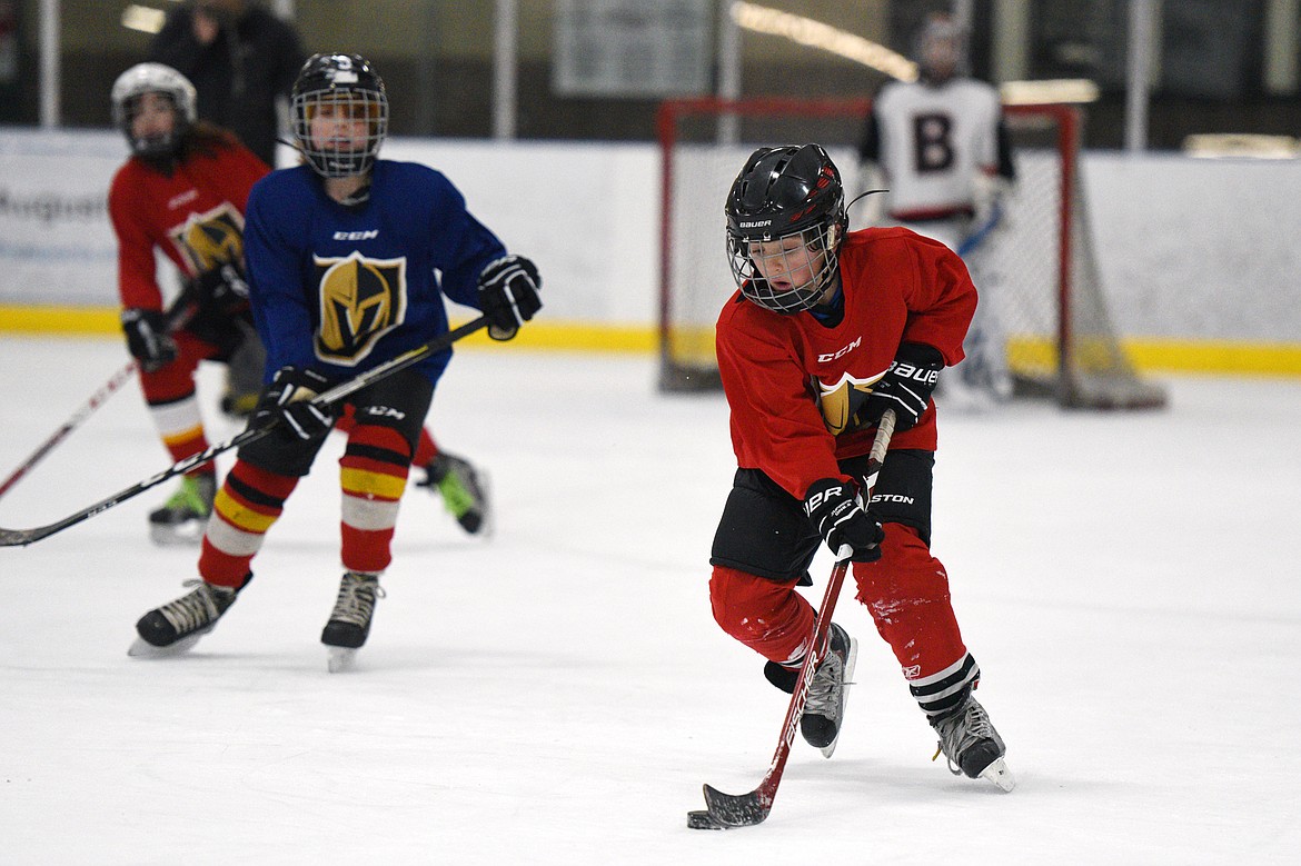 A red team player skates with the puck as the red and blue teams square off during a Yeti League game.
