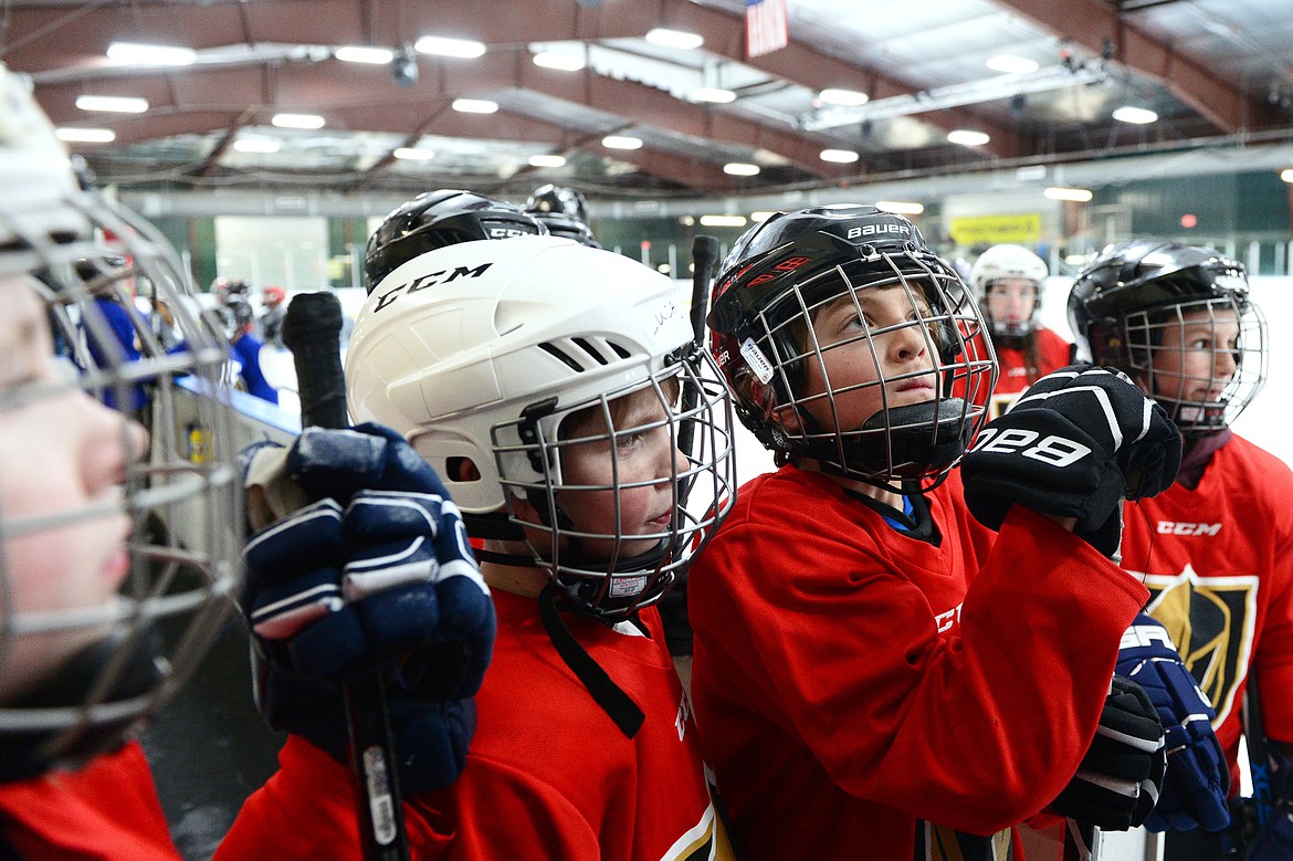 Players on the red team listen to their coach before heading out onto the ice.