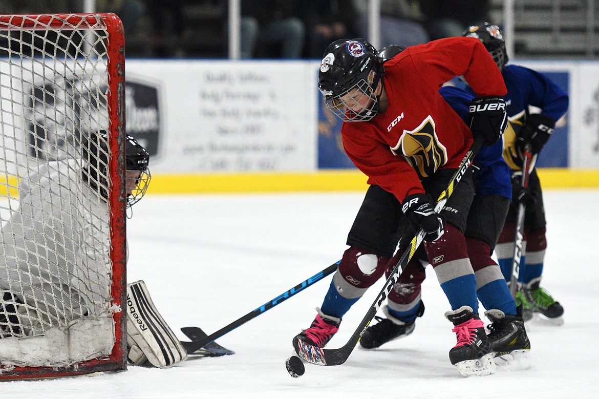 A player on the red team shoots the puck on goal as the red and blue teams square off.