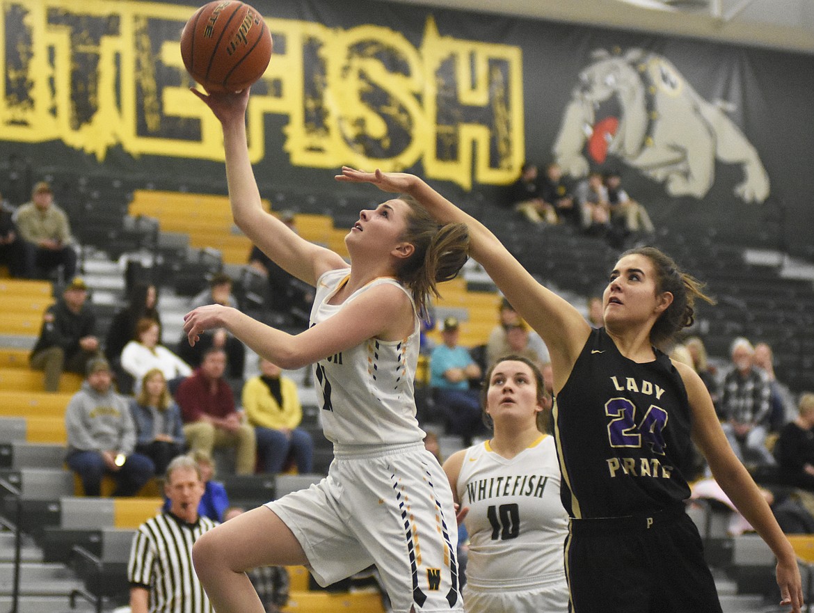 Claire Carloss fights off the contact for the layup against Polson on Friday. (Daniel McKay/Whitefish Pilot)