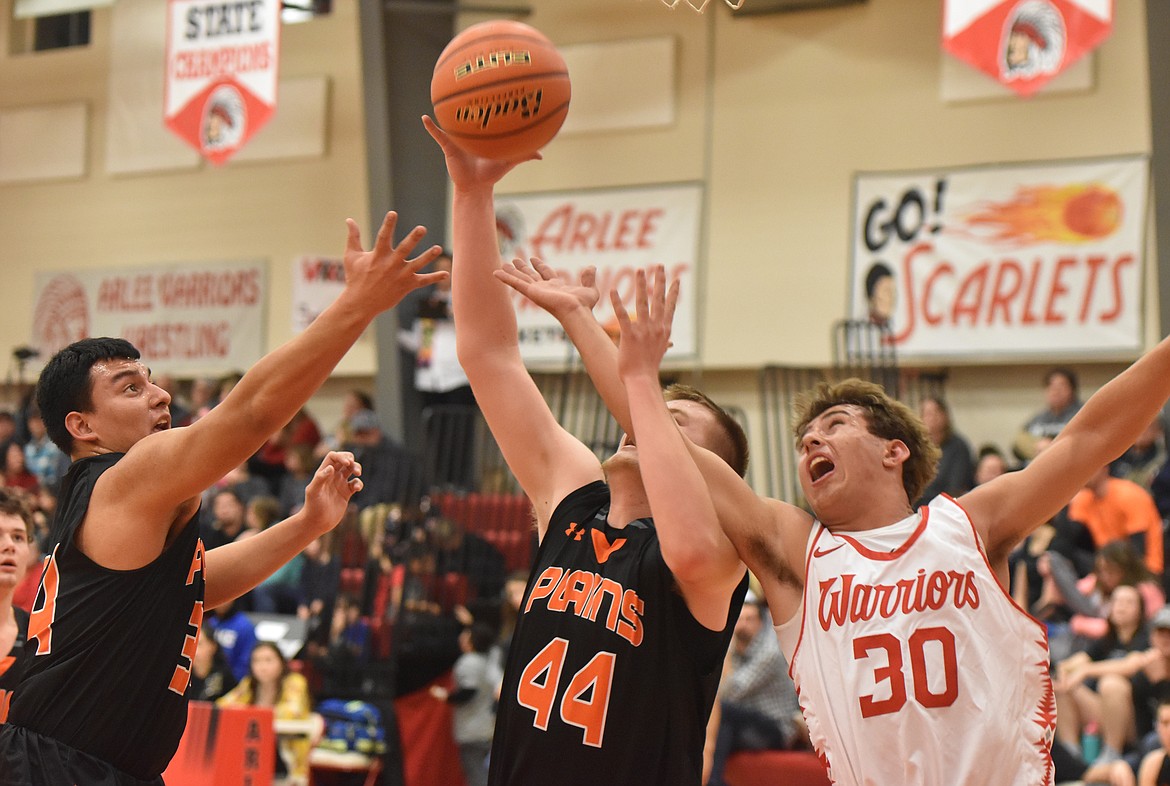 Plains senior Derick Curry (44) and junior Esvin Reyes (34) battle Lane Schall (30) of Arlee for a rebound during last Thursday&#146;s District 14C contest at Arlee. The Warriors used a 17-2 third-quarter run en route to a 73-50 win. (Joe Sova/Clark Fork Valley Press)