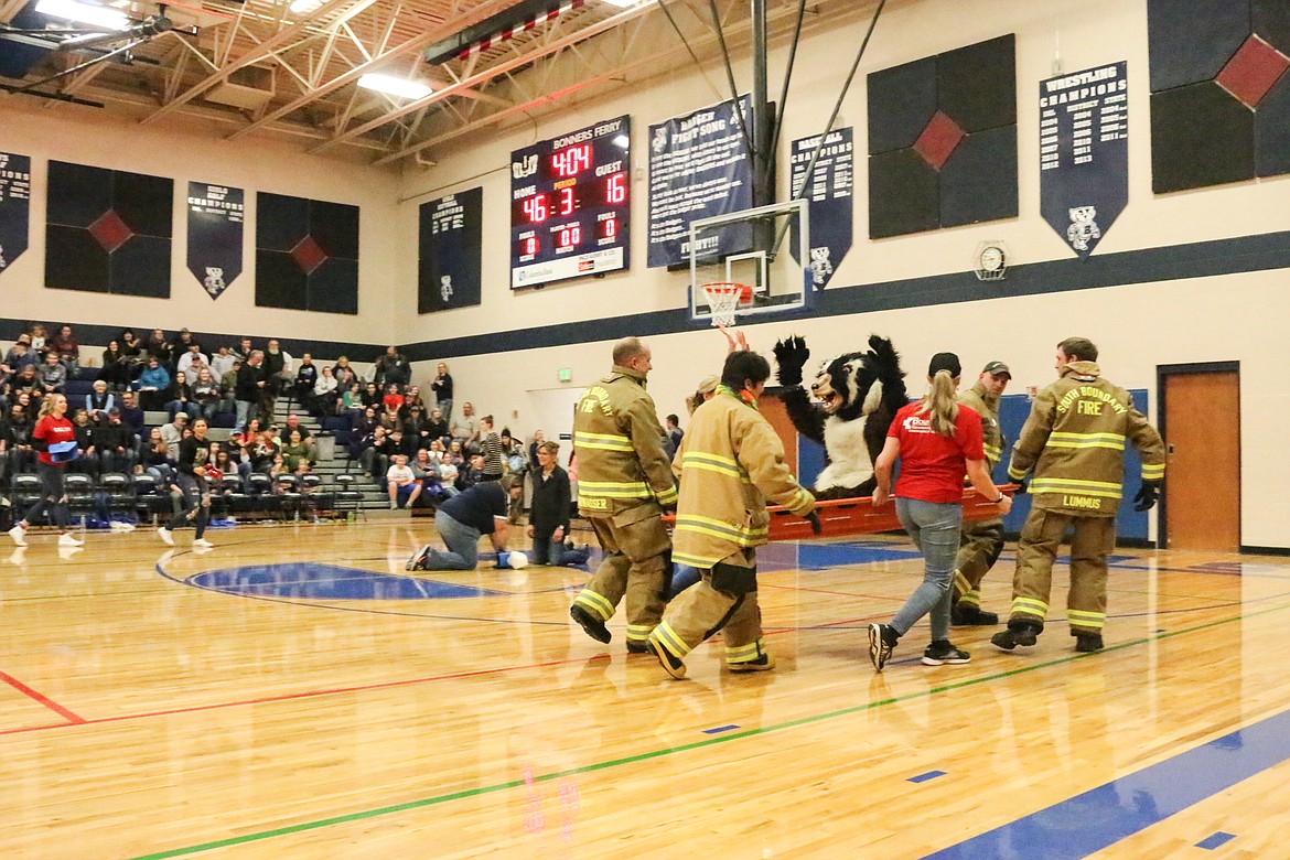 South Boundary Firefighters carry Buddy Badger from the gym.