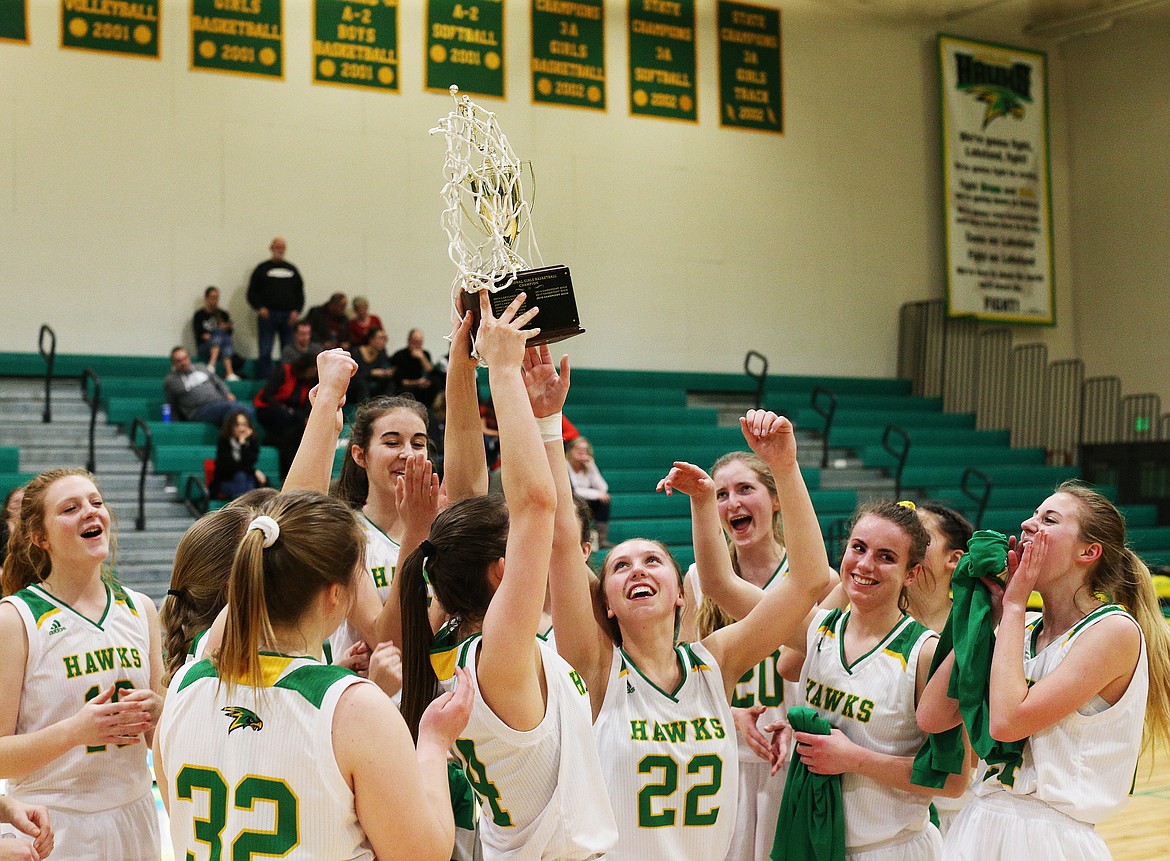 Lakeland&#146;s Darby McDevitt hoists the 4A Region 1 Championship trophy next to her teammates after they defeated Moscow 42-34 Friday night at Hawk Court. (LOREN BENOIT/Press)