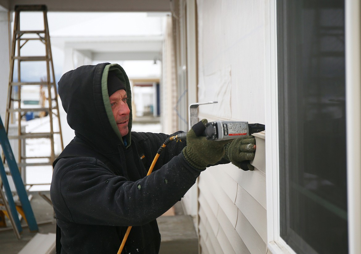 Jeff Dallen, with Armor Exteriors in Coeur d'Alene, installs siding to a house on Wellington Avenue in Post Falls on Wednesday. (LOREN BENOIT/Press)