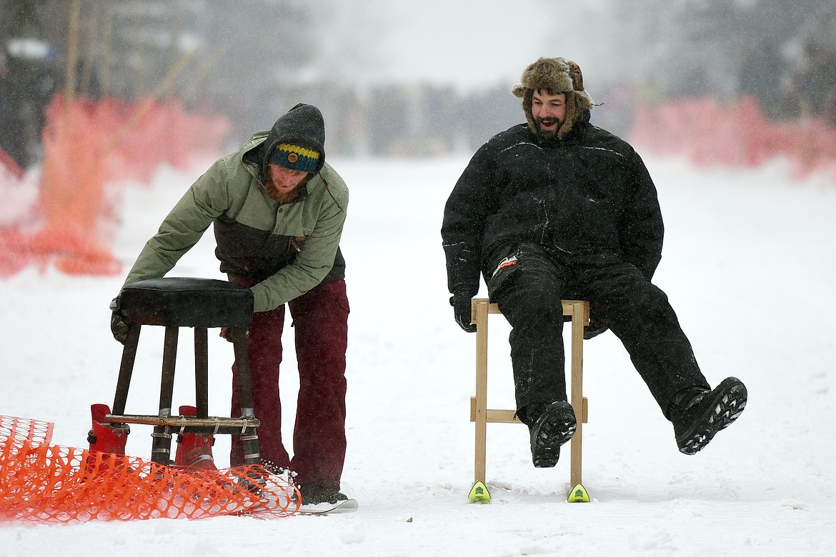 A racer laughs as he passes his opponent who got stuck in fencing after a crash during Barstool Ski Races at Cabin Fever Days in Martin City on Saturday. (Casey Kreider/Daily Inter Lake)