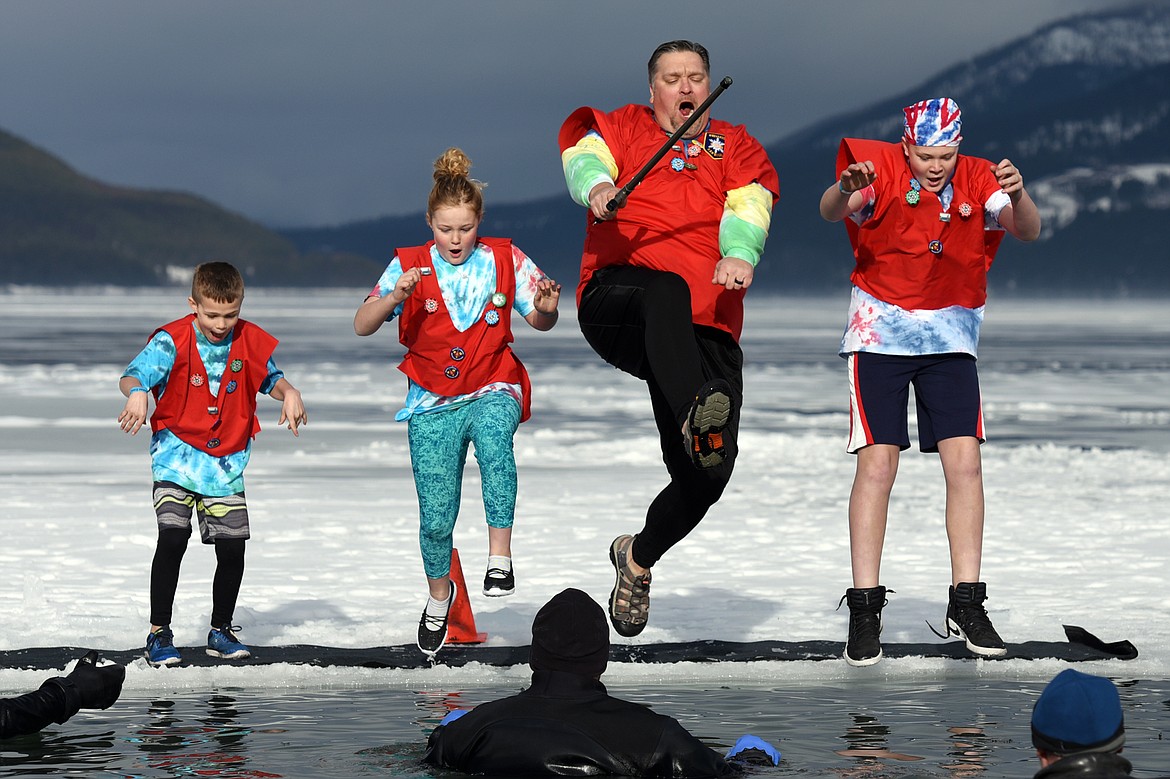 Dr. Kanyon Smith, third from left, Prime Minister LX in the Whitefish Winter Carnival Royal Court, leaps into Whitefish Lake during the Whitefish Winter Carnival Penguin Plunge 2019 on Saturday. (Casey Kreider/Daily Inter Lake)