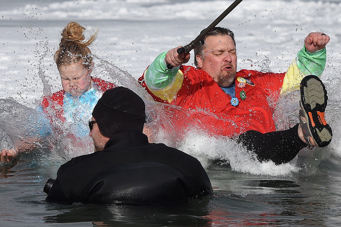 Dr. Kanyon Smith, right, Prime Minister LX in the Whitefish Winter Carnival Royal Court, leaps into Whitefish Lake during the Whitefish Winter Carnival Penguin Plunge 2019 on Saturday. (Casey Kreider/Daily Inter Lake)