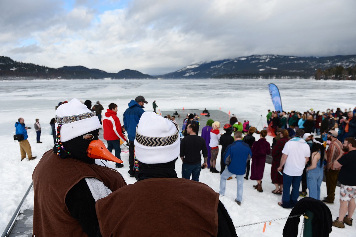 Two ladies wearing penguin costumes for Whitefish Winter Carnival watch participants leap into Whitefish Lake during the Whitefish Winter Carnival Penguin Plunge 2019 on Saturday. (Casey Kreider/Daily Inter Lake)