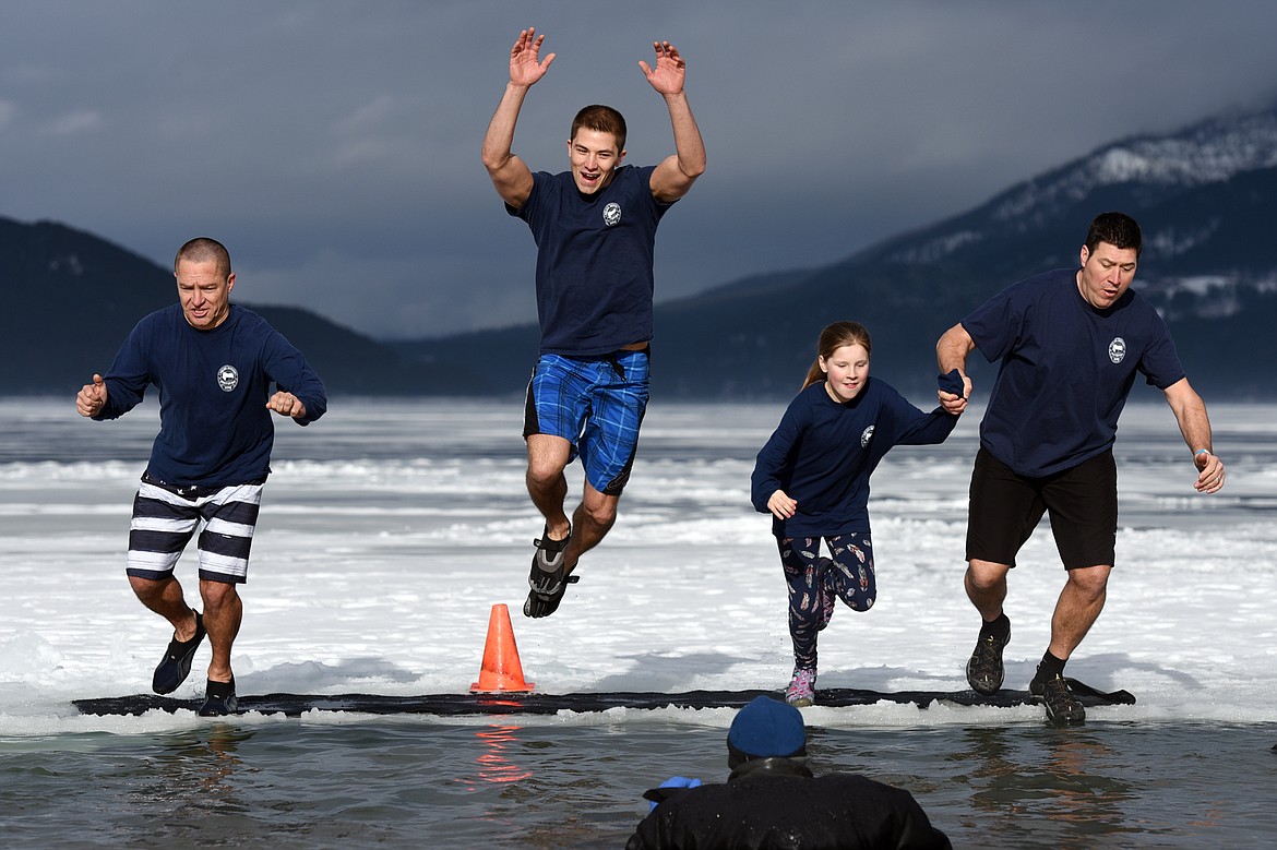 Participants representing the Whitefish Police Department leap into Whitefish Lake during the Whitefish Winter Carnival Penguin Plunge 2019 at City Beach on Saturday. (Casey Kreider/Daily Inter Lake)