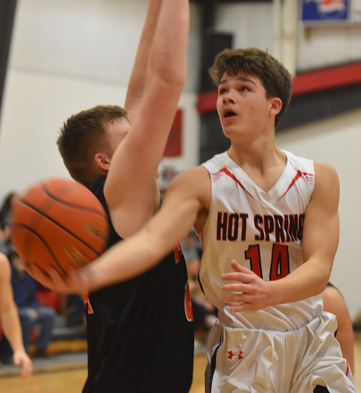 HOT SPRINGS junior guard Brandon Knudsen (14), scooping the ball to the hoop past Derick Curry, netted 32 points in leading the Savage Heat to a 66-35 win over Plains last Friday night. (Joe Sova/Clark Fork Valley Press)