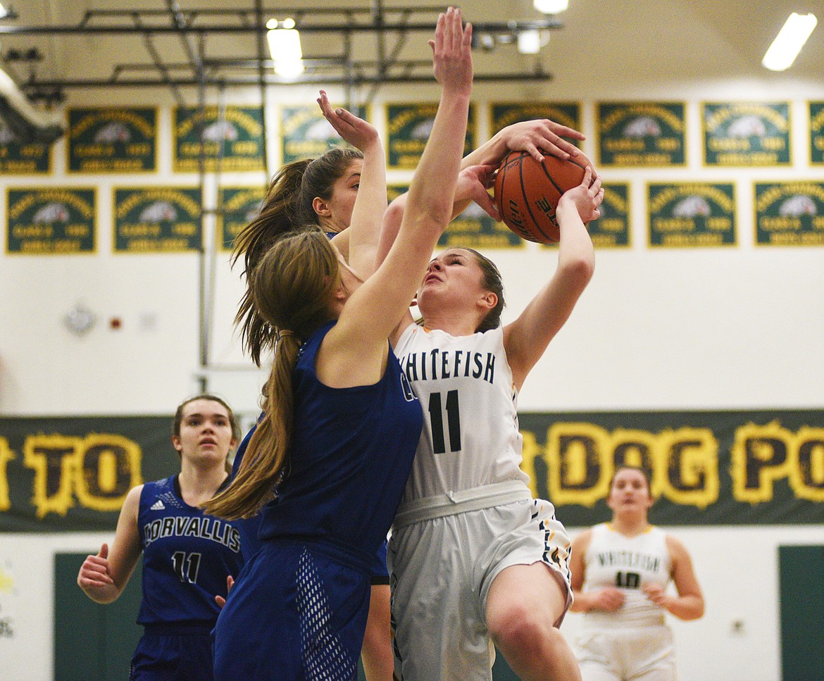 Claire Carloss gets hammered by defenders against Corvallis on Friday. (Daniel McKay/Whitefish Pilot)