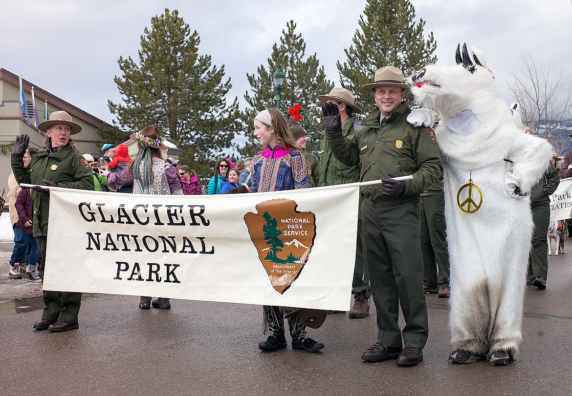 Tracy Ammerman and Phil Wilson along with a mountain goat carry the Glacier National Park banner.