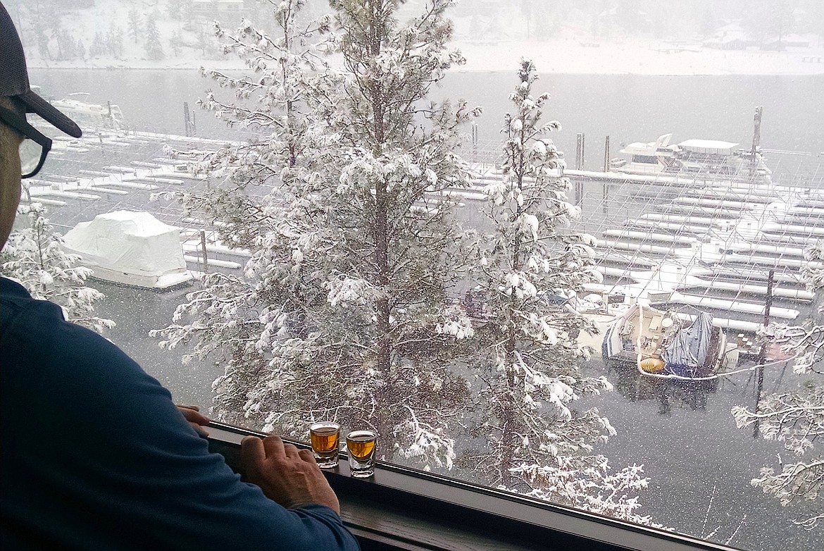 With his sunken boat being recovered in the background on the Spokane River at the Red Lion Templin&#146;s Hotel marina in Post Falls, John Leavell takes shots of his courtesy whiskey shots that were given to him by hotel staff. Leavell and friend Dave Couch watched the recovery efforts from the hotel&#146;s restaurant on Friday. (BRIAN WALKER/Press)